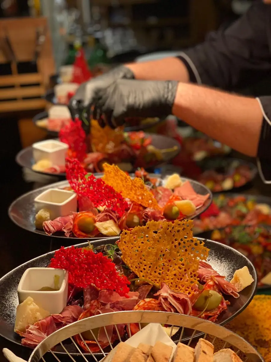 Antipasti-Teller mit Prosciutto, Salami und Parmesan-Chips werden angerichtet